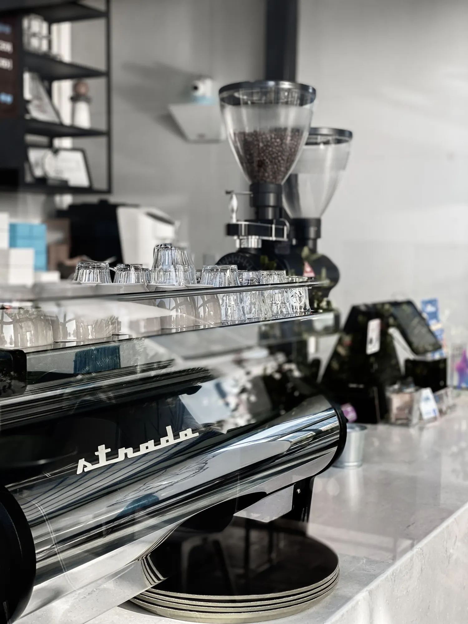A polished espresso machine and grinders on a stone café counter