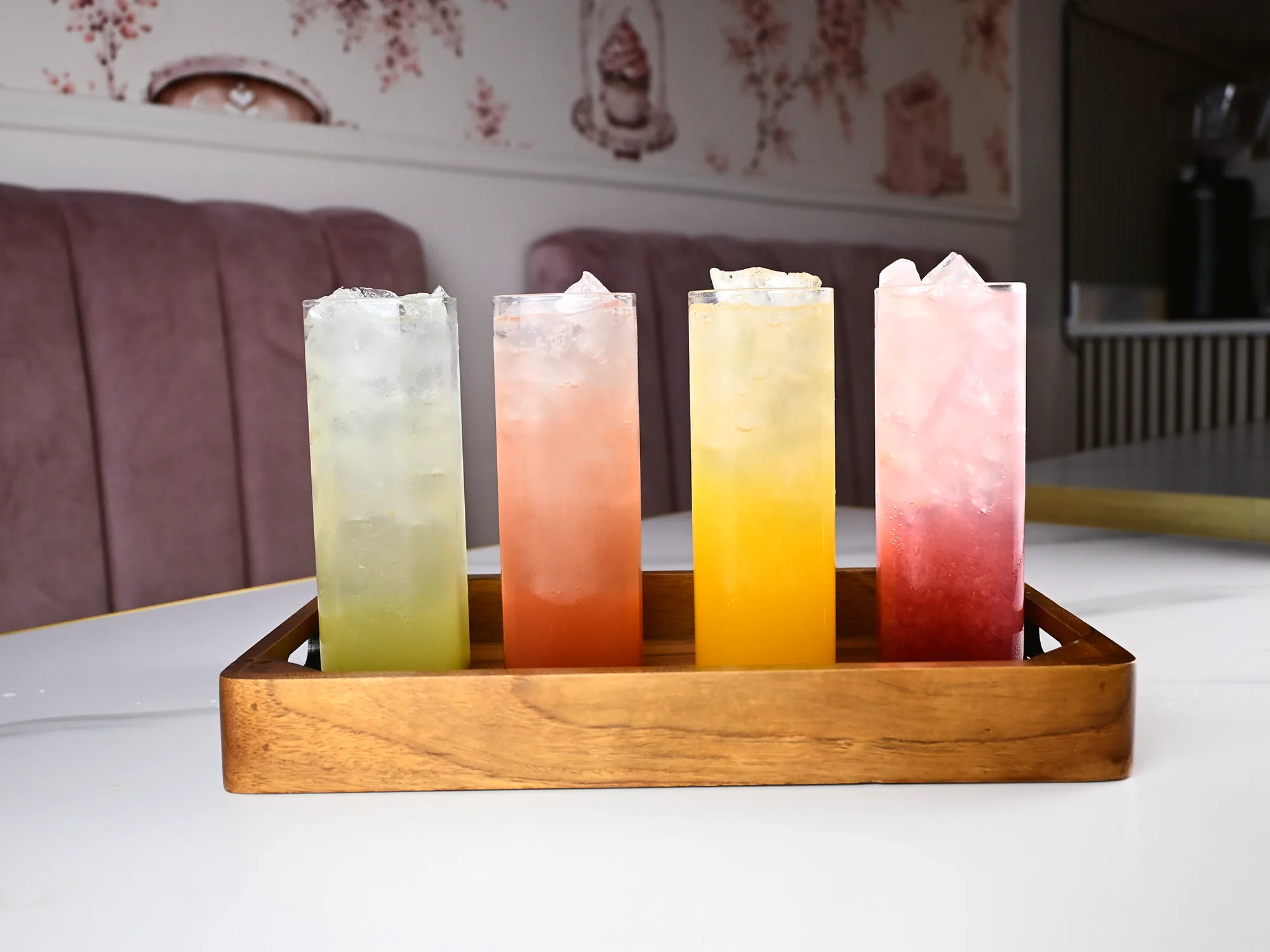 Four refreshers in a wooden tray, graduated from lemon through orange to raspberry