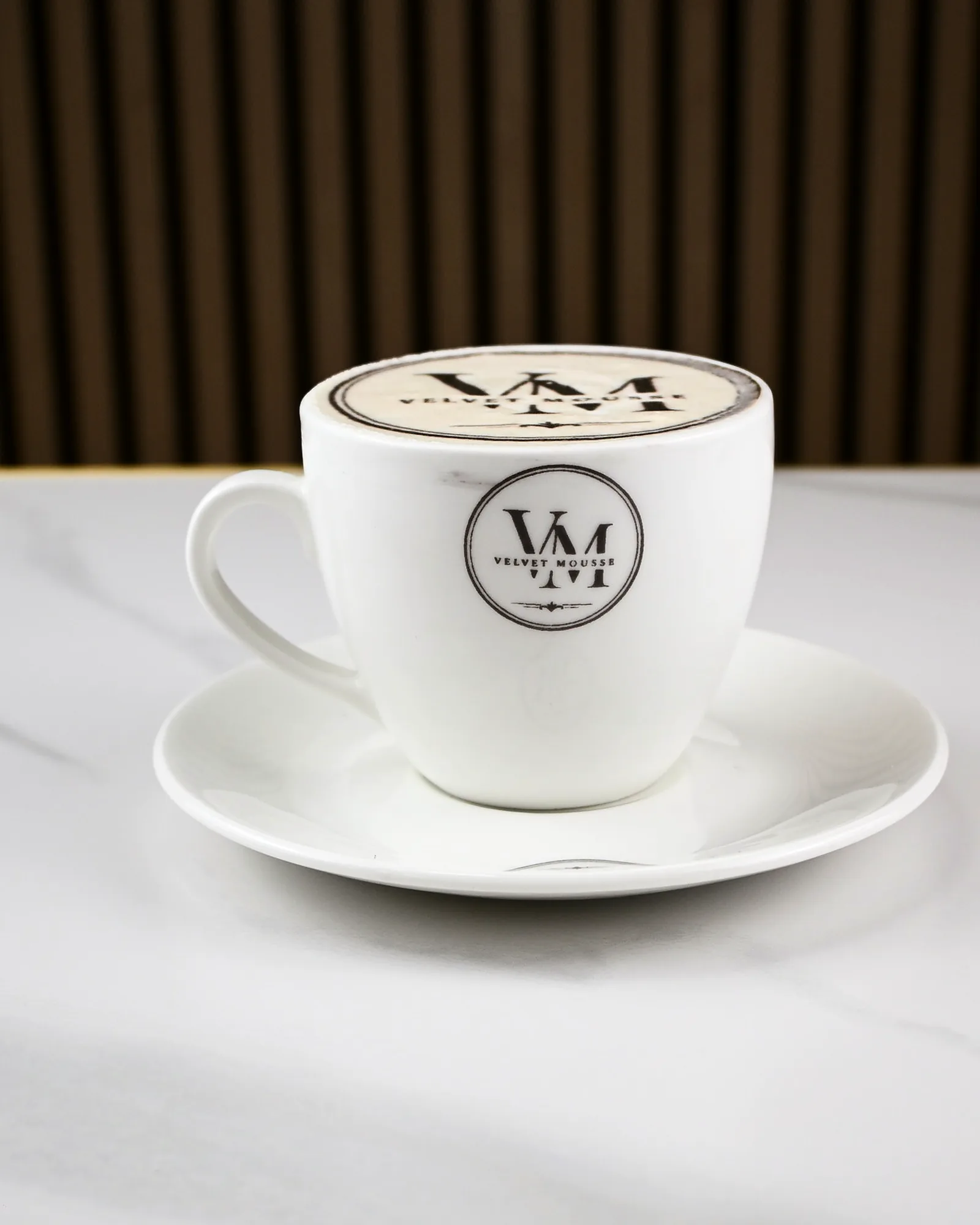 A Velvet Mousse cup and saucer on a marble counter